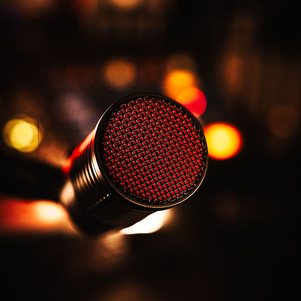 front of the DynaCaster mic black wire mesh grille with red windscreen showing through and lights in the background
