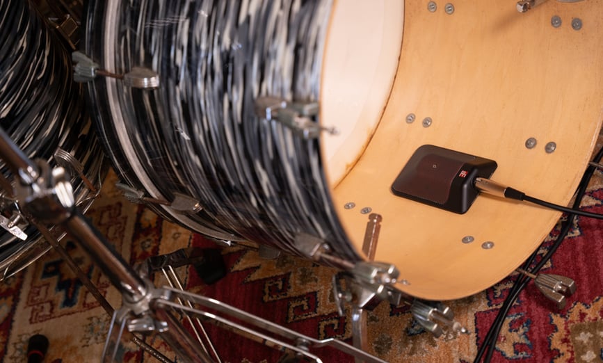 a gray bass drum without a front drum head with the BL8 inside of the drum laying on the inner natural wood