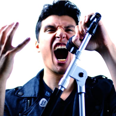 Frank Palangi with a white background screaming into a V7 microphone. There is a microphone stand in the image with a blue hue.