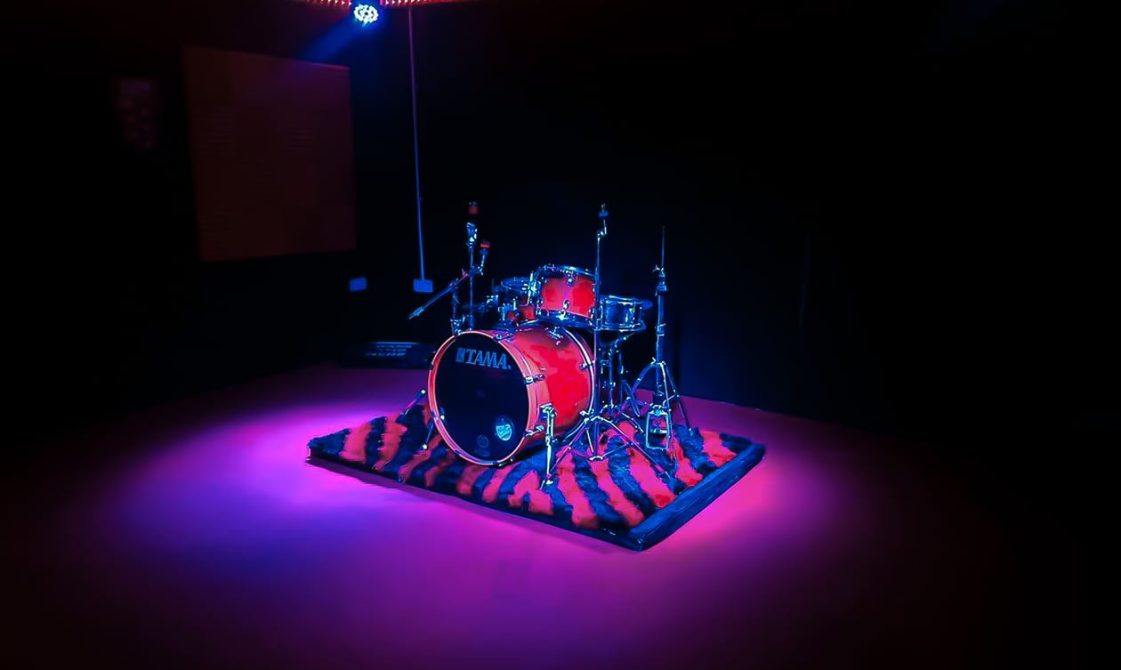 Drum set on stage with purple and red hue.