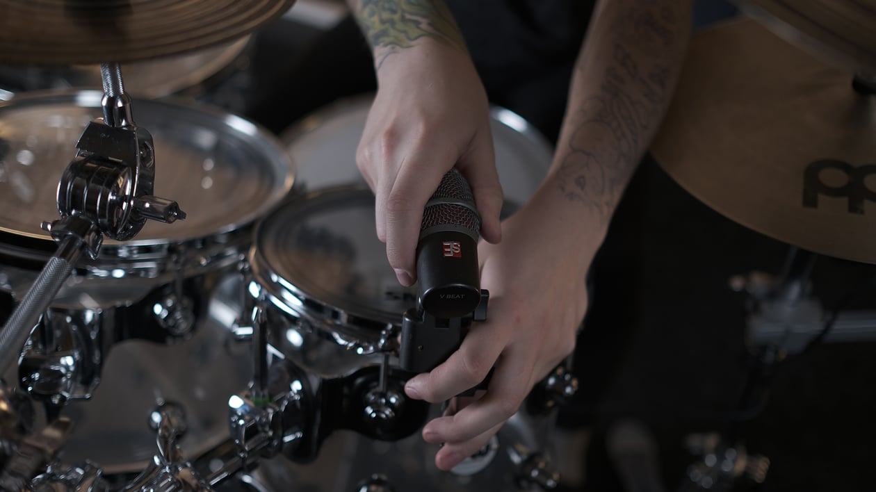 Maxim Moskovkin clamping a dark gray V Beat microphone with the V Clamp to the rim of a tom.
