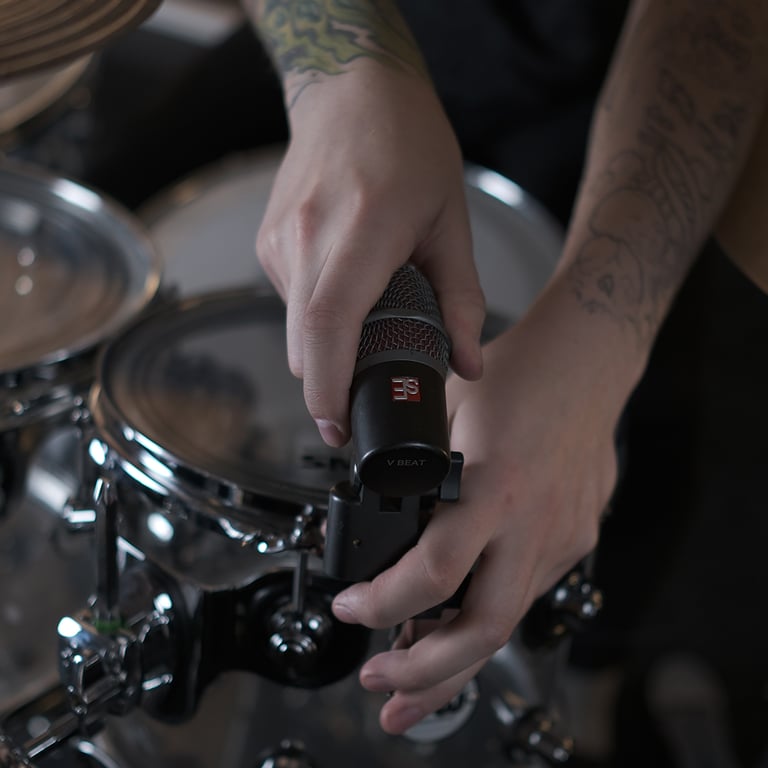 Maxim Moskovkin clamping a dark gray V Beat microphone with the V Clamp to the rim of a tom.